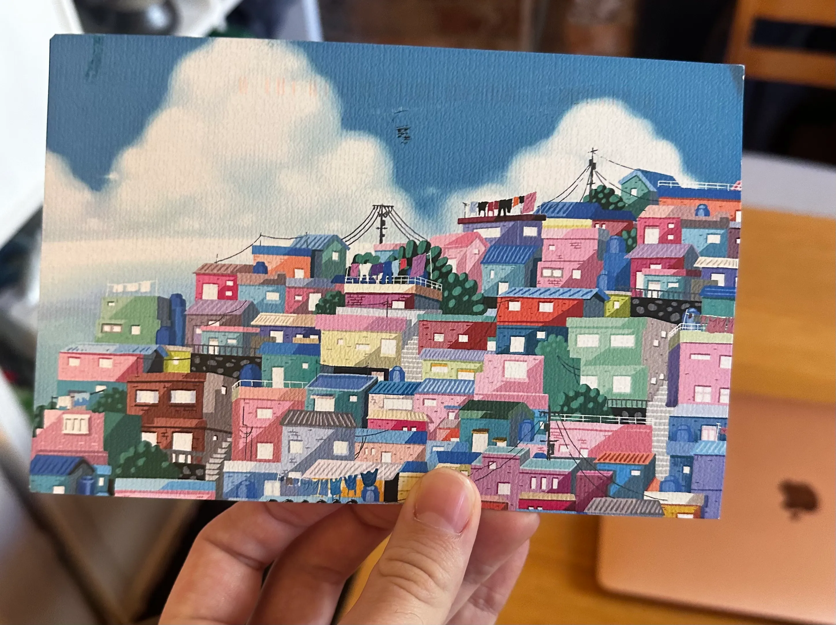 A postcard with an image on it, in comic style. A terraced hill of colourful houses.