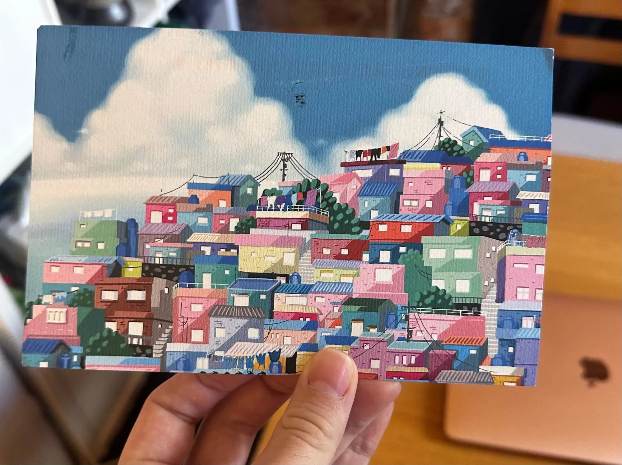 A postcard with an image on it, in comic style. A terraced hill of colourful houses.